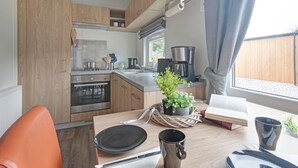 Une cuisine moderne avec des meubles en bois, une cuisinière, une machine à café et une fenêtre avec des rideaux.