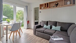 Una sala de estar moderna con un sofá gris, suelo de madera y una zona de comedor con una mesa y sillas.
