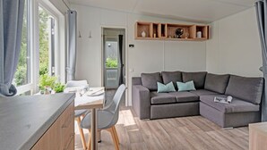Una sala de estar moderna con un sofá gris, una mesa de comedor con sillas y una cocina con armarios de madera y una encimera.