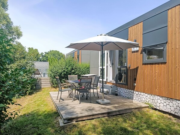 A patio with a table and chairs, an umbrella, and a wooden deck. - Tiny Haus Sonnendeck Martina by Interhome (Beilngries)
