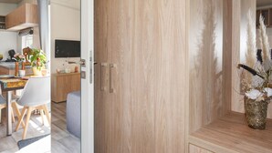 Een moderne keuken met houten kastjes, een eethoek met een tafel en stoelen, en een decoratieve plant op het aanrecht.