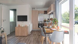Een moderne keuken met houten kastjes, een inbouwoven en een eethoek met een tafel en stoelen.