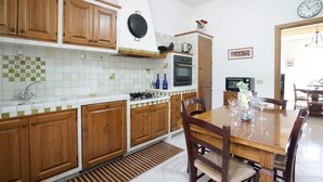 Una cocina con armarios de madera, una estufa y un comedor con mesa y sillas.