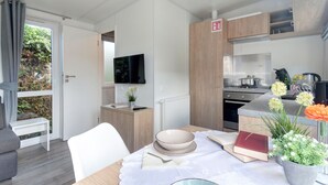 Eine moderne Küche mit Flachbildfernseher, Holzschränken und einem Essbereich mit Tisch für zwei Personen.