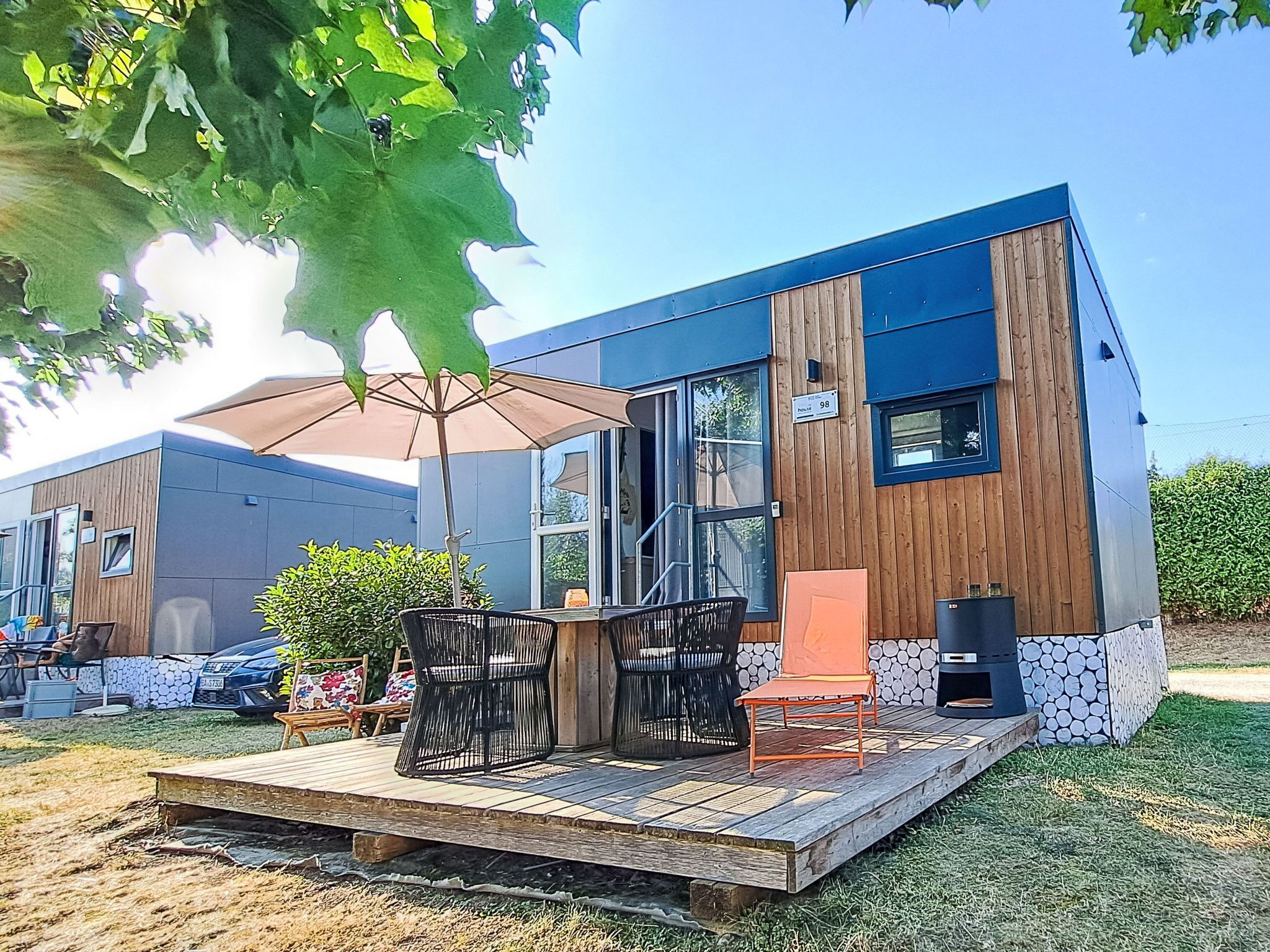 Een modern gebouw met een terras, zitplaatsen buiten en een barbecue.