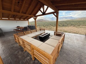 Un espace extérieur abrité, aménagé avec du mobilier en bois et offrant une vue sur les montagnes.