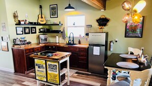 Une cuisine avec un plan de travail en bois, un réfrigérateur, une table à manger avec des sets de table et une chaise.
