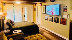 Une chambre à coucher avec un lit, une télévision, une guitare et divers posters accrochés au mur.