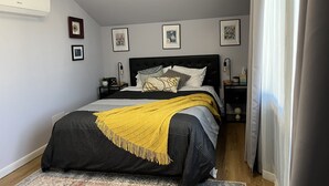 Une chambre à coucher avec un lit, des tables de chevet, une commode, une lampe et des tableaux encadrés accrochés au mur.