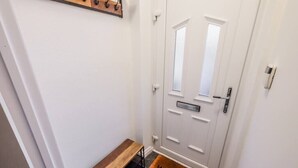 A white door with a 'WELCOME' mat, a bench, and a coat rack above it. - Sleek 2B/1B Retreat in Lindley, Huddersfield (Lindley)