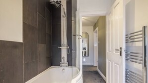 A modern bathroom with a freestanding bathtub, a shower area, and a walk-in closet with a mirrored closet door. - Sleek 2B/1B Retreat in Lindley, Huddersfield (Lindley)