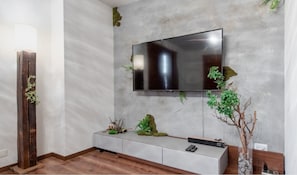 Relax in this stylish living room with a flat-screen TV, console table, and lush greenery.