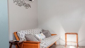 Uma sala de estar moderna com um sofá, uma pequena mesa de madeira e um objeto decorativo na parede.