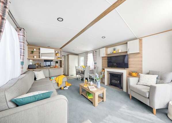 A modern living room with a sofa, a coffee table, a fireplace, and a TV mounted on the wall.