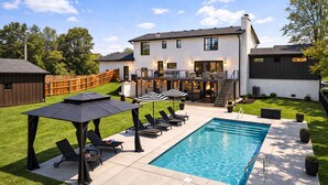 A modern house with a backyard pool, outdoor seating, and a covered patio area. - Spacious Retreat with Heated Pool-Hot Tub-Games-Bar-Near Keeneland&Bourbon Trail (Lexington)