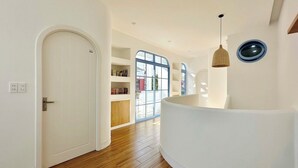 A modern interior with a wooden floor, white walls, a white door, and a curved white bench. - Serena Villa, Da Nang city, Vietnam, 3 bedrooms, near the beach (Đà Nẵng)