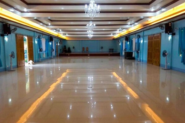 A spacious hall with a polished floor, a chandelier, and blue walls with wooden doors.