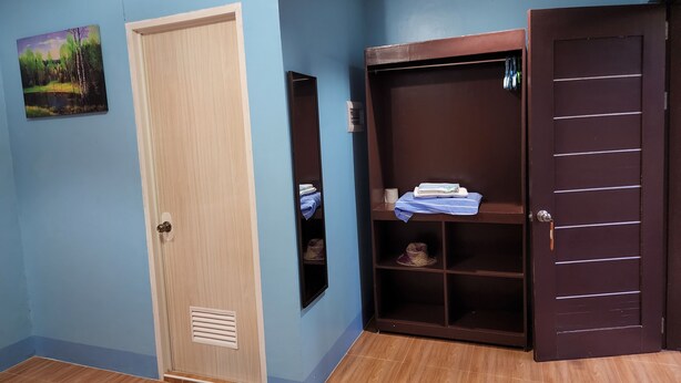 A room with a blue wall, a wooden door, a wardrobe with shelves, and a small rug. - MJS Campsite and Mountain Resort (Balilihan)