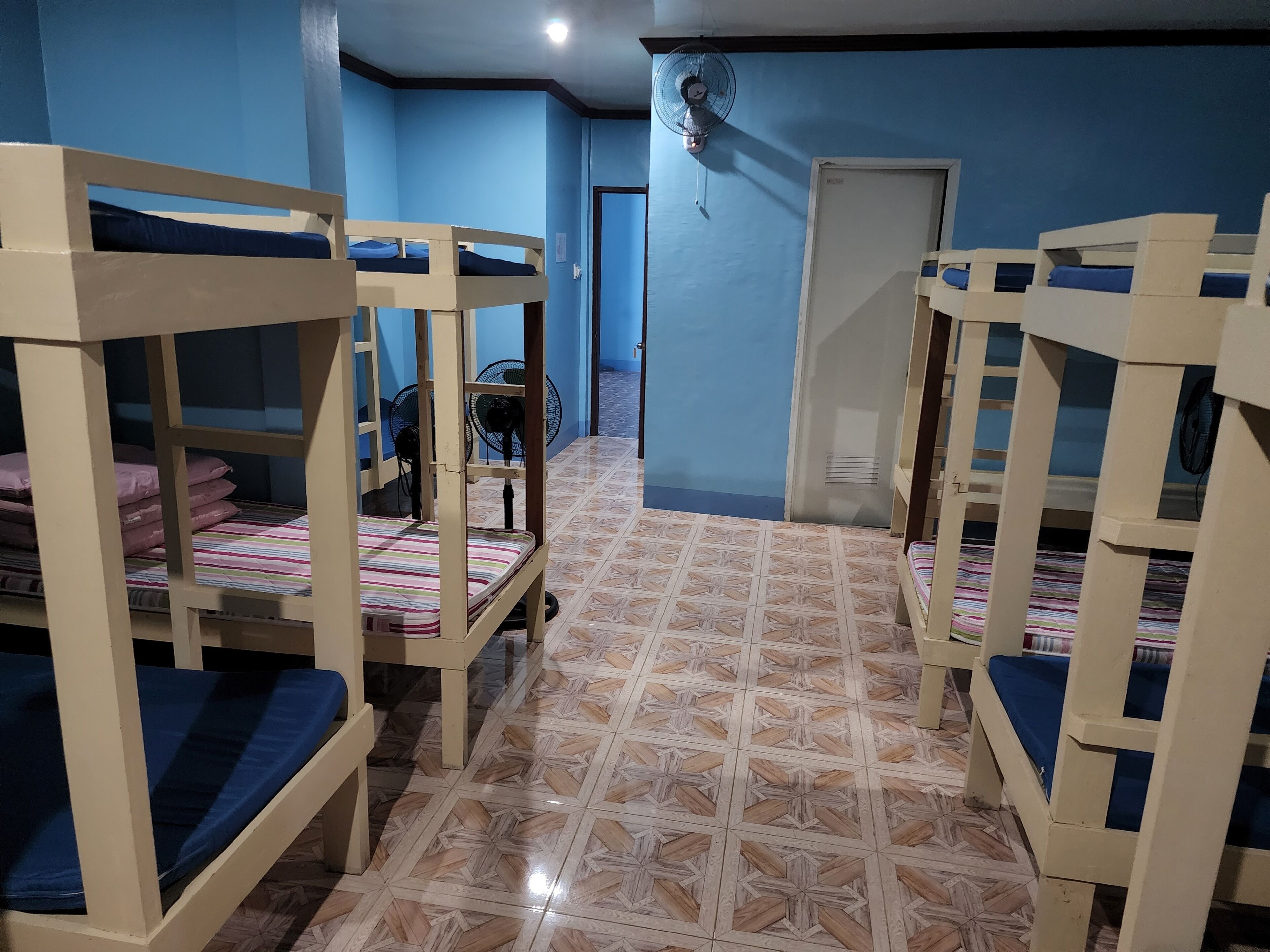 A room with bunk beds, a fan, and a tiled floor.