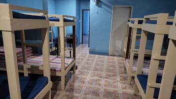 A room with bunk beds, a fan, and a tiled floor.