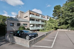 Um edifício moderno com um estacionamento e um carro estacionado em frente.