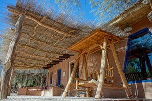 Una construcción rústica de madera con techo de paja, vigas de madera y un banco.