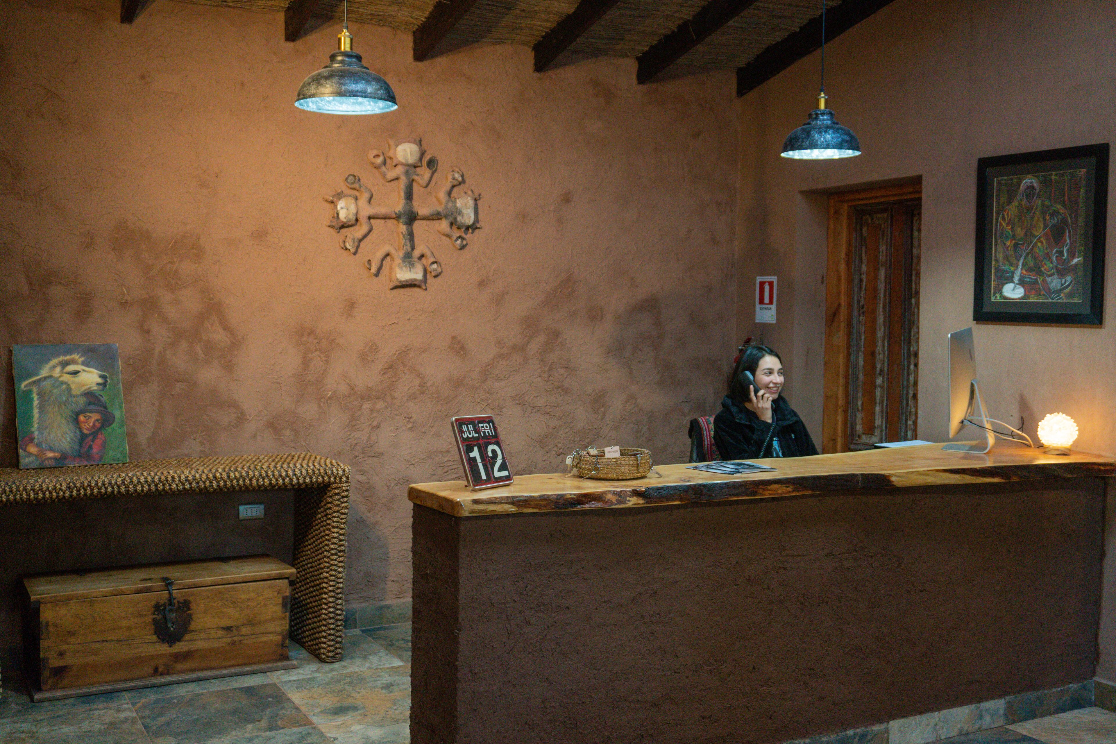A rustic reception desk with a date sign, a woven bench, and a wooden chest.