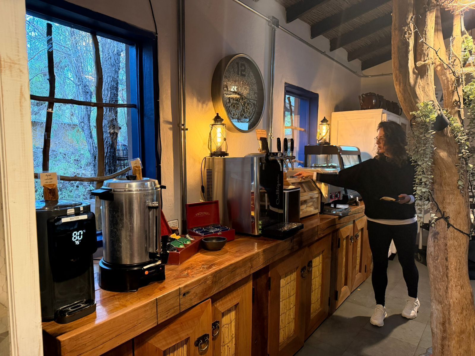 A rustic kitchen with a coffee machine, a water dispenser, and a wooden counter.