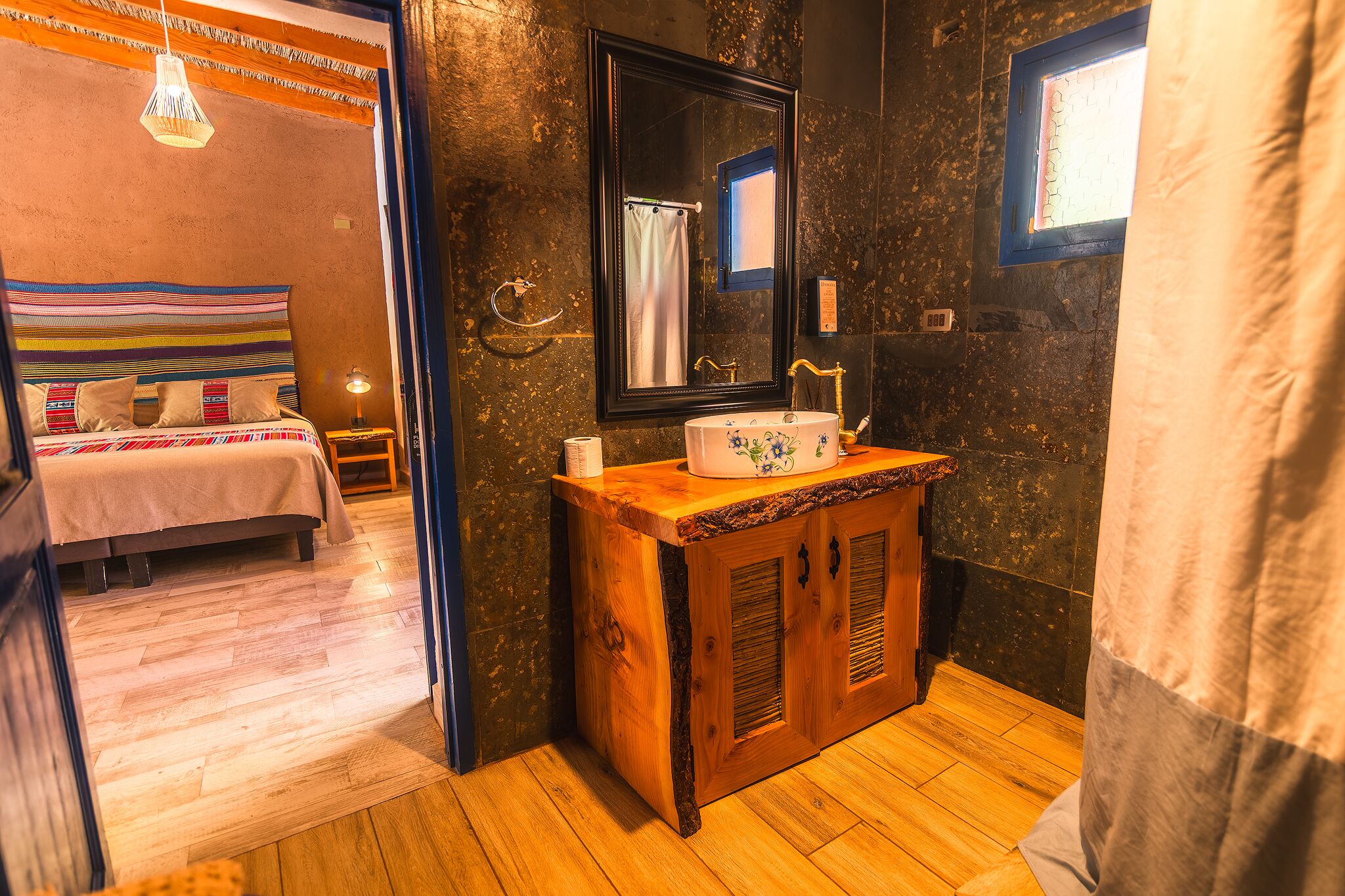 A bedroom with a bed, a wooden dresser, a mirror, and a window.