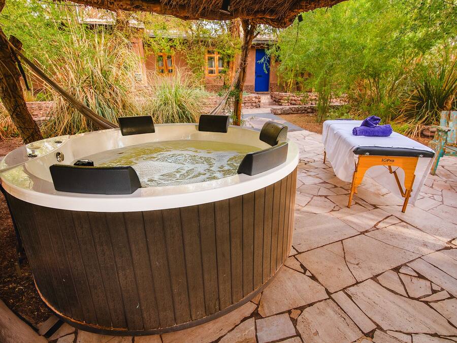 Un jacuzzi con revestimiento de madera, una mesa con una toalla y una puerta azul al fondo.