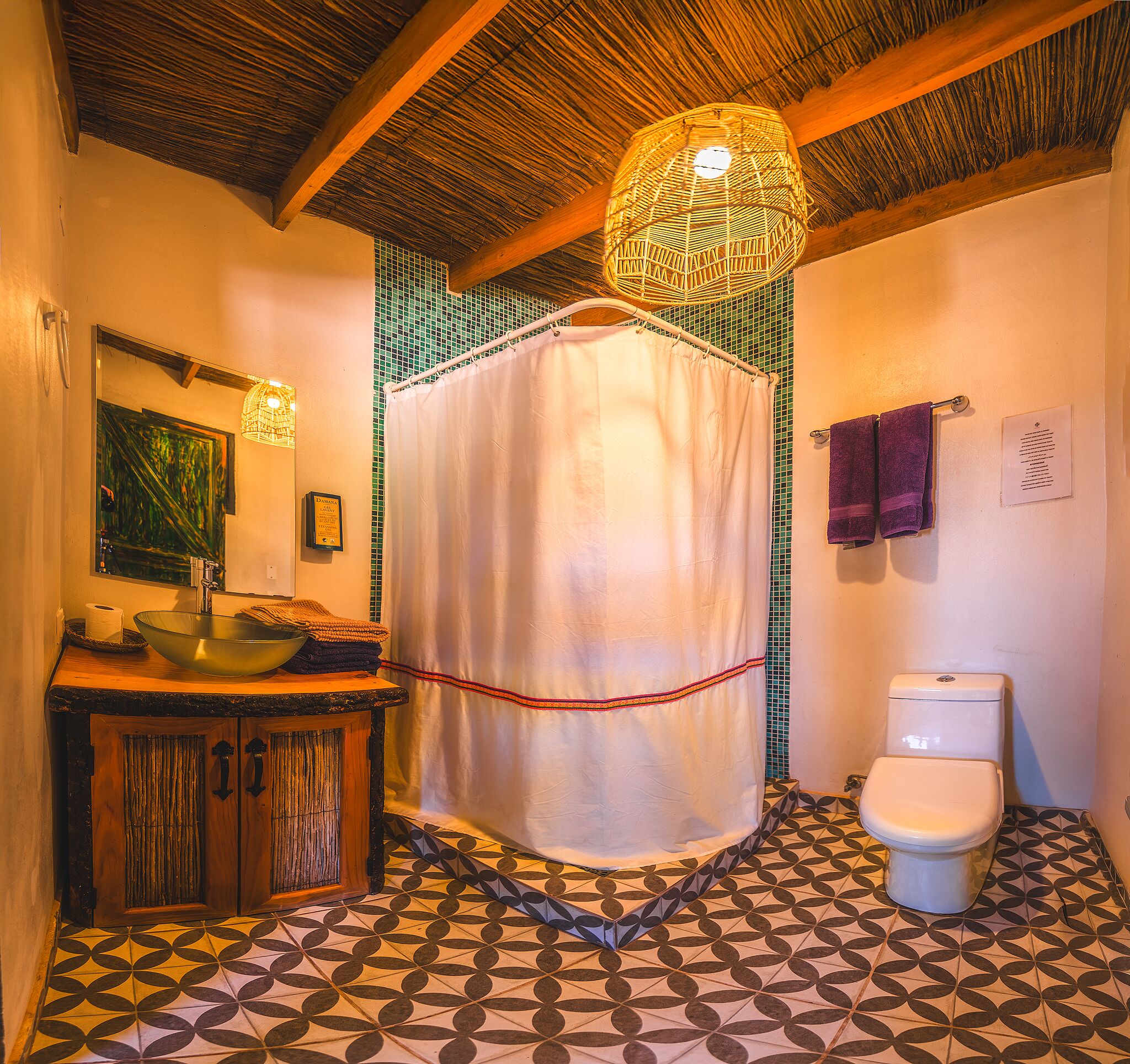 A bathroom with a patterned floor, a wooden sink, a toilet, and a shower curtain.