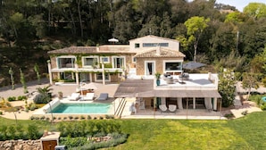 Una casa de dos pisos amb piscina, mobiliari exterior i jardí.
