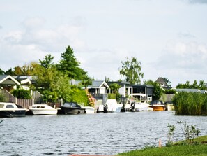 A waterfront property with boats docked, a grassy area, and houses in the background.