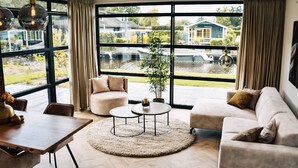 Un salon spacieux avec une grande fenêtre, une table basse ronde, un canapé et une table à manger.