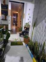 Vestíbulo de hotel con suelo de baldosas, plantas en macetas, un banco y una pared decorada con mariposas.
