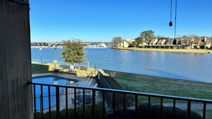 A view from a balcony overlooking a body of water with a pool and a fenced area. - Waterfront modern condo on Walden at the lake Conroe (Montgomery)