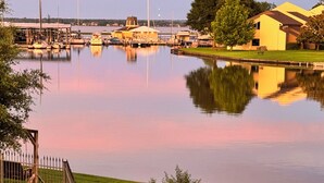 A waterfront property with a dock, boats, and a grassy area with lounge chairs. - Waterfront modern condo on Walden at the lake Conroe (Montgomery)
