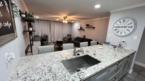 A modern kitchen with granite countertops, a built-in sink, and grey cabinets. - Waterfront modern condo on Walden at the lake Conroe (Montgomery)