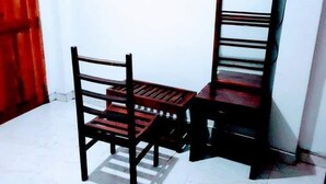 A corner of a room with a wooden chair and a wooden table. - Black And White Kandy Guest House  (Kandy)