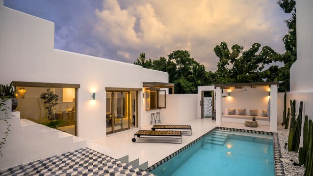 A modern outdoor pool area with a geometric tile pattern, a seating area with a sofa and chairs, and a cactus garden. - Villa Oasi 2 by Alfred in Bali (Pecatu)