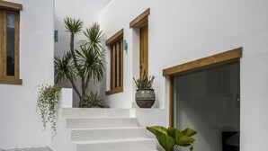 A modern building with white walls, wooden-framed windows, and a large glass door. - Villa Oasi 2 by Alfred in Bali (Pecatu)