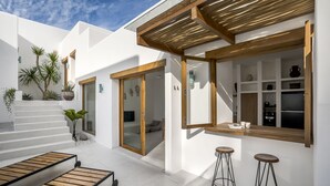 A modern outdoor kitchen area with a wooden pergola, a bar counter, and two stools. - Villa Oasi 2 by Alfred in Bali (Pecatu)