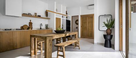Eine moderne Küche mit Holztisch und Bank, weißen Schränken und einem Blumentopf.