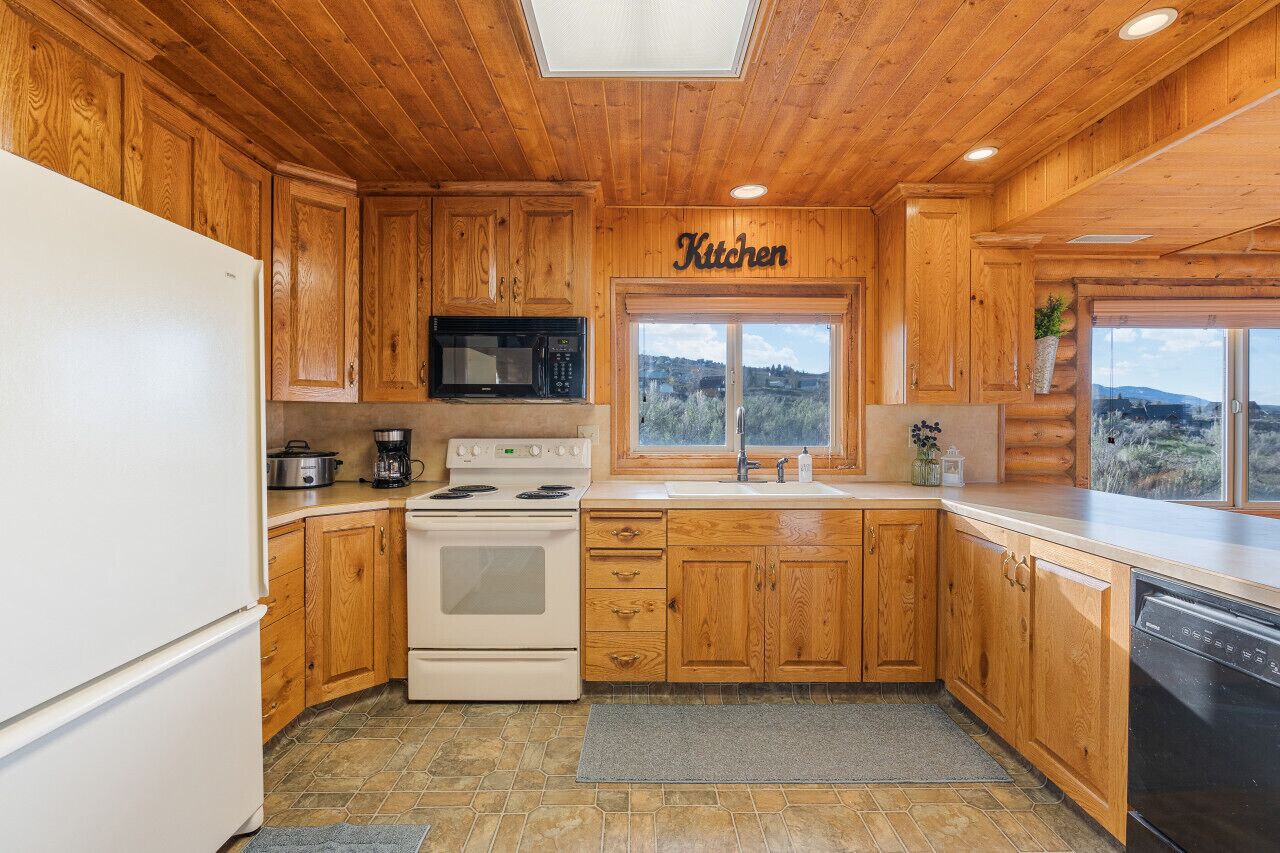 A kitchen with wooden cabinets, a stove, a microwave, and a sink.