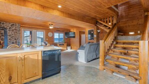 A spacious log cabin interior with a kitchen, dining area, and a staircase.