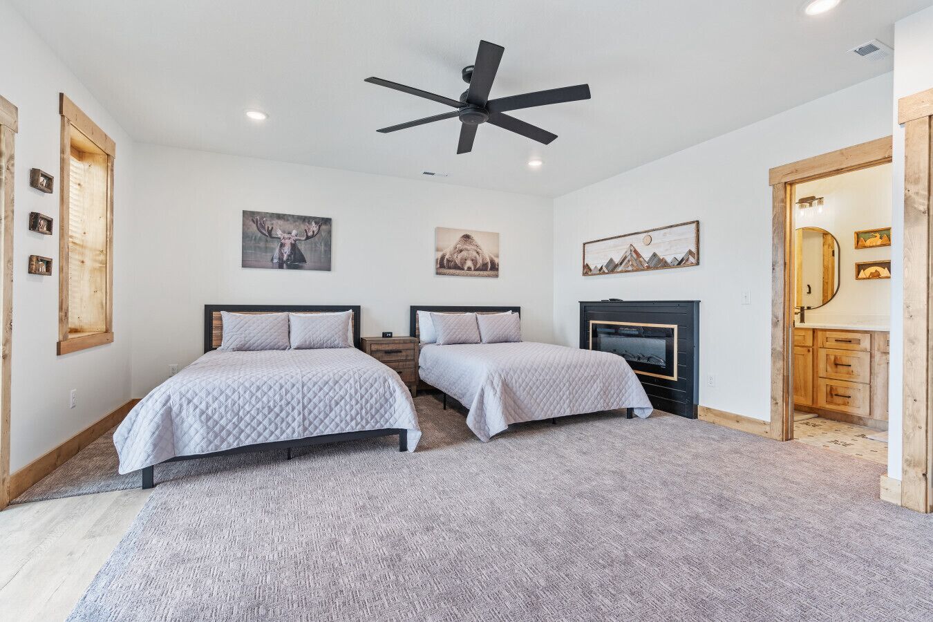 A bedroom with two beds, a ceiling fan, and a fireplace.