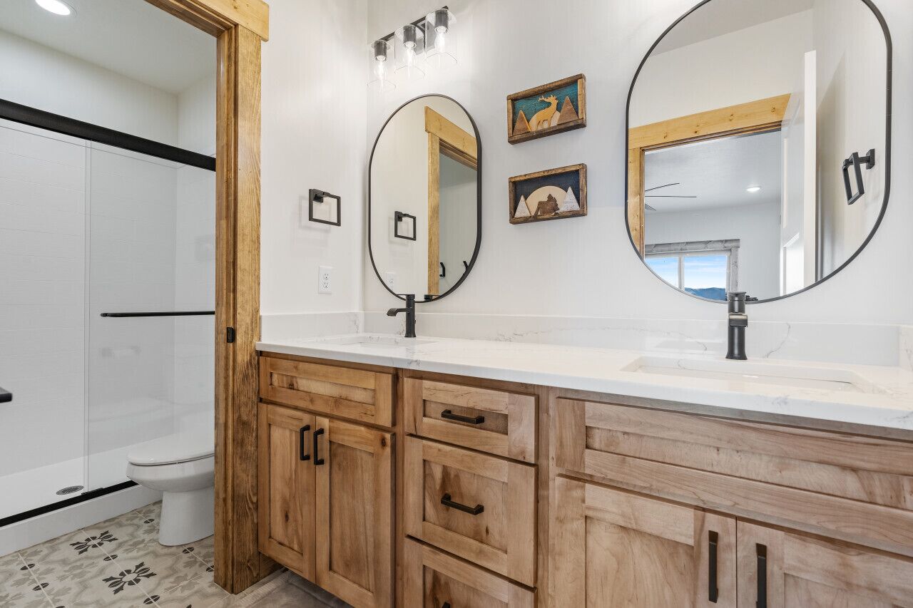 A bathroom with two sinks, wooden cabinets, and a large mirror.