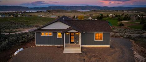 A two-story house with a front porch, a driveway, and a view of the surrounding landscape.