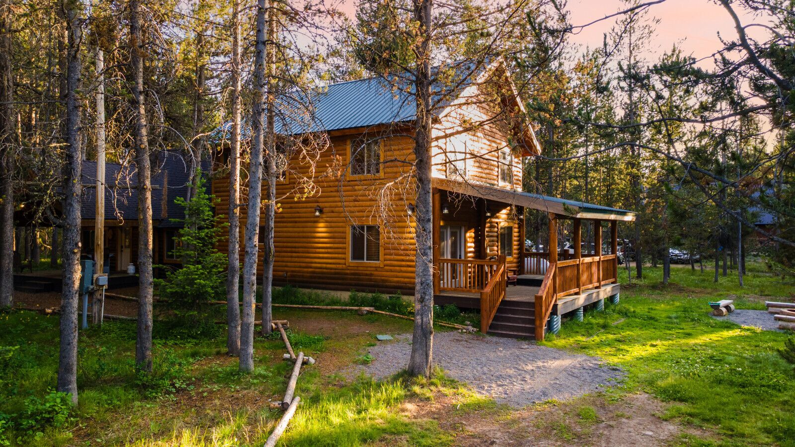 A log cabin with a porch and steps leading to a deck.