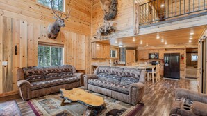 A log cabin interior with a living room, kitchen, and dining area.